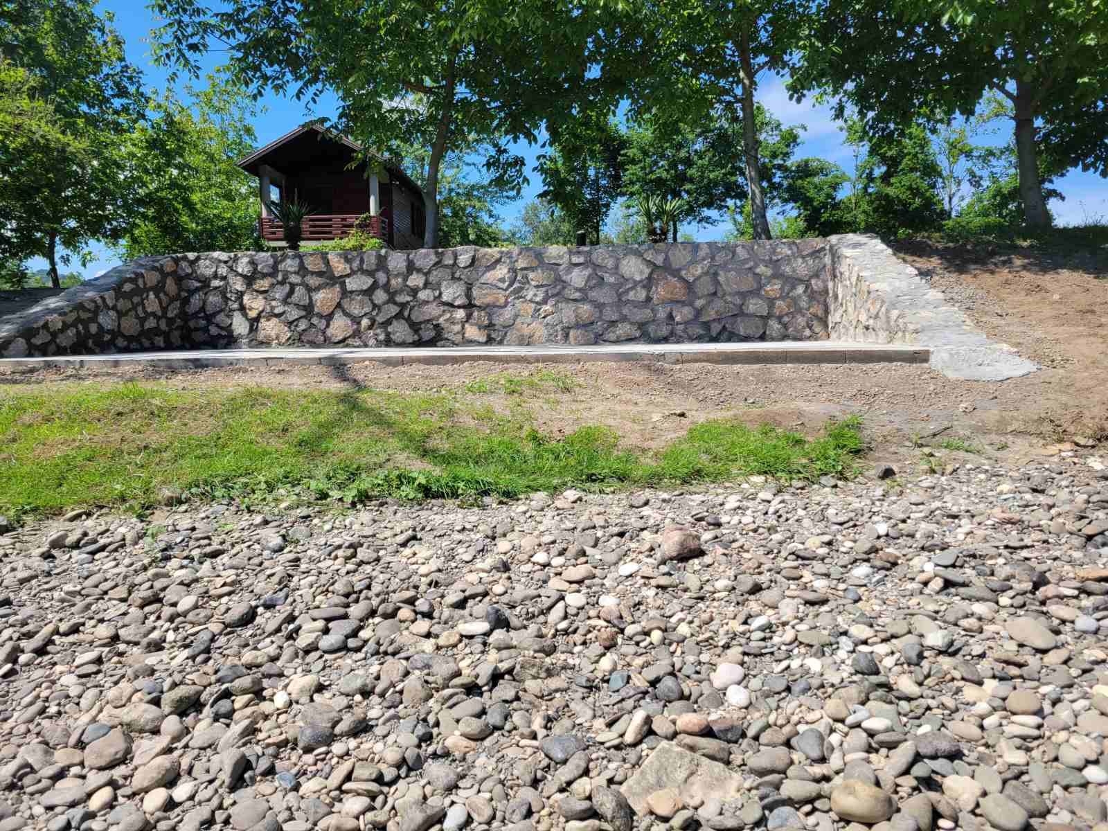 Kameni zid sa vikendicom u pozadini